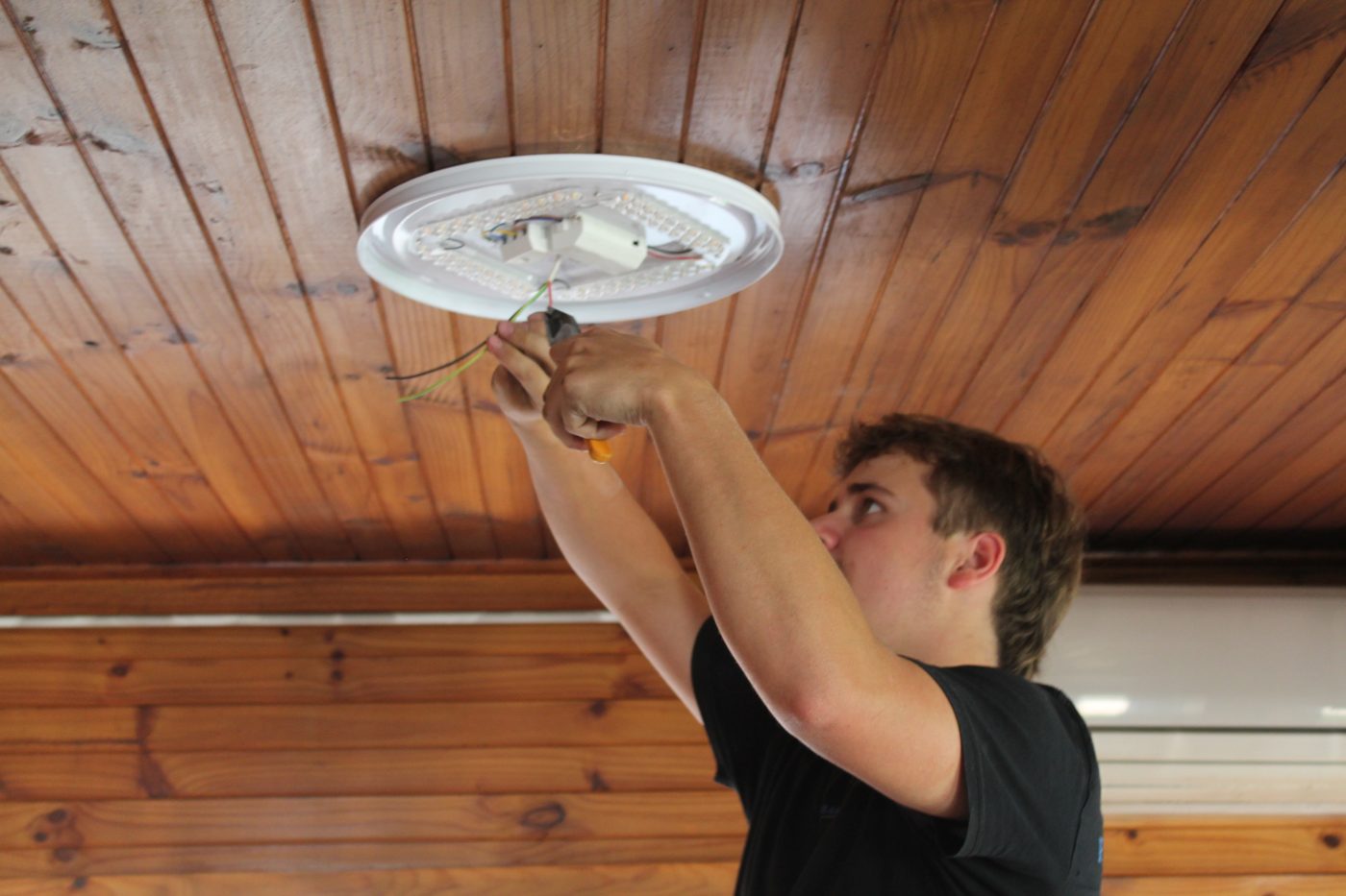 Fraser Electrical technician installing a ceiling light